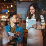 A waitress takes an order from a guest holding a menu