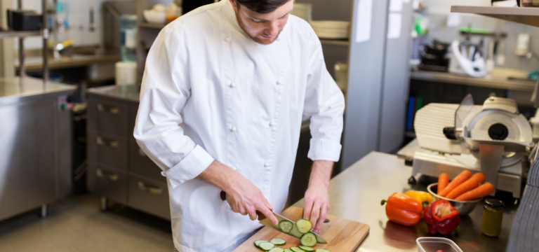 Cook cutting vegetables in restaurant kitchen