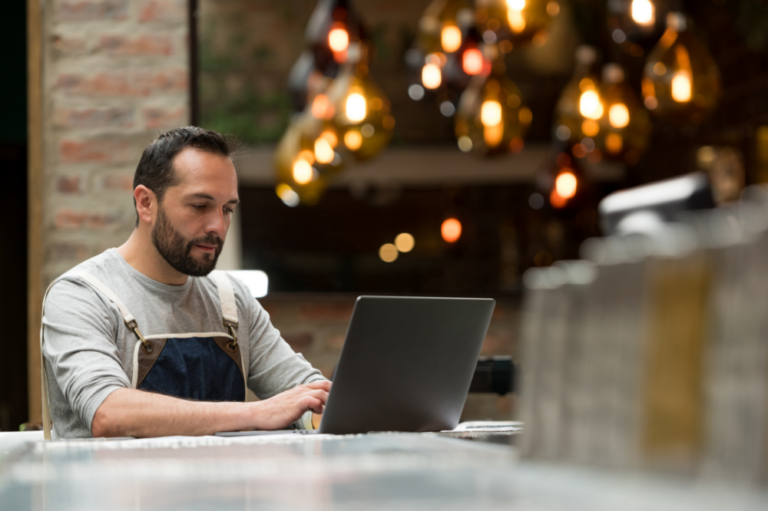 Man working in restaurant looking at laptop