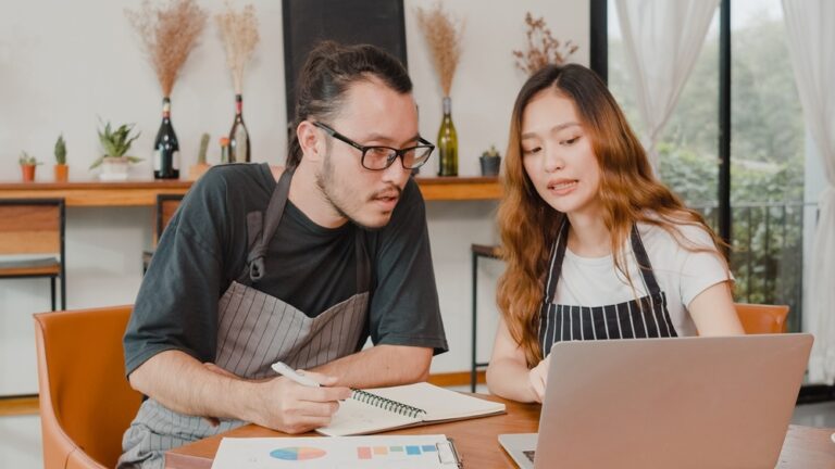 Two restaurant owners using a laptop discussing finances at a cafe