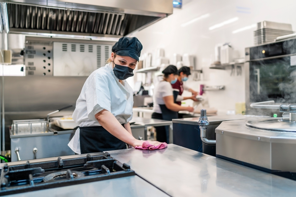 Female cook cleaning kitchen after work