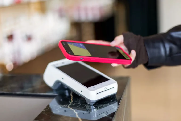 Customer using a smartphone to make a contactless payment on a restaurant POS terminal