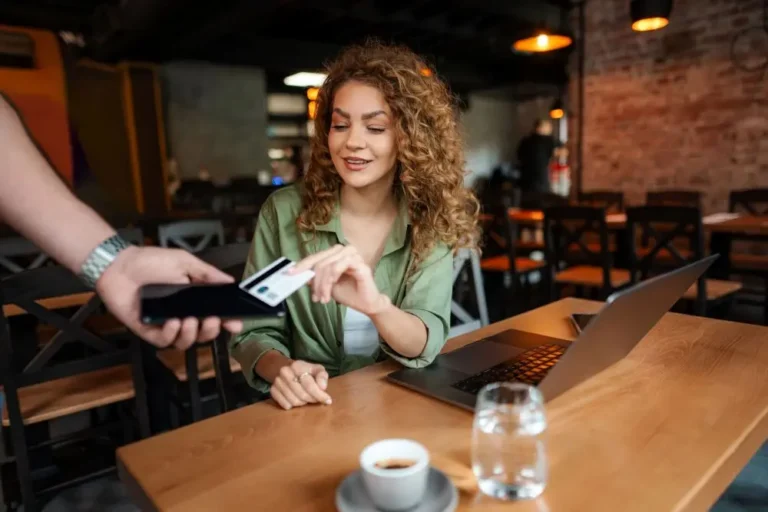 Customer making a contactless card payment at a restaurant table using a mobile payment device