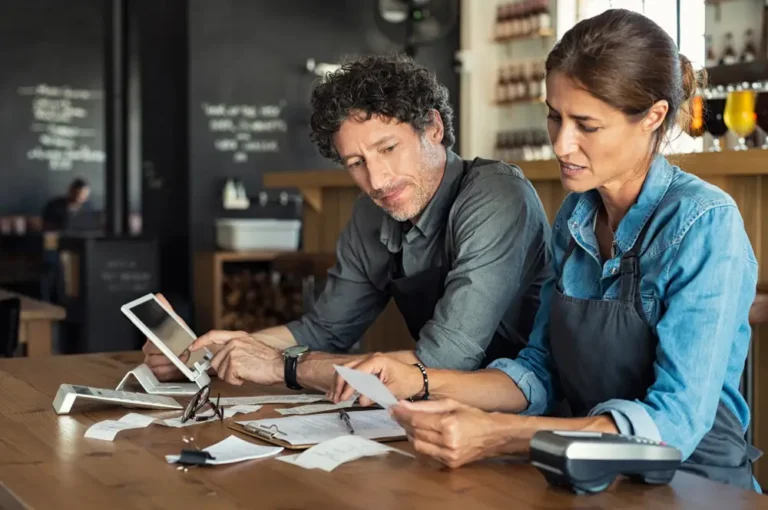 Man and woman sitting in cafeteria discussing finances for the month