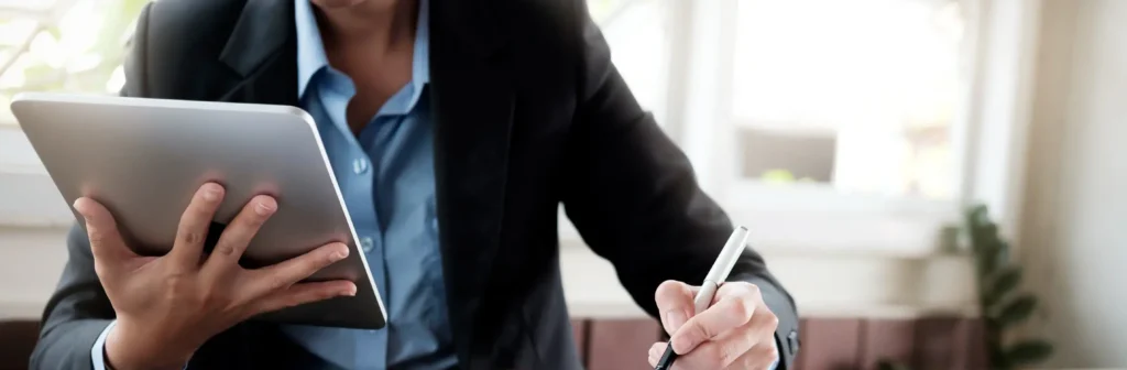 Woman with tablet in hand working at table.