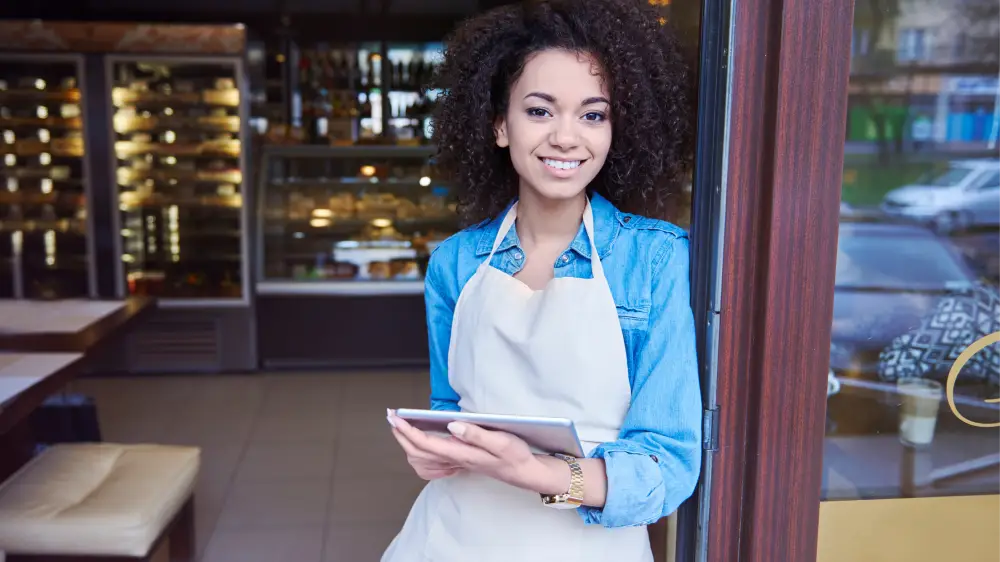 A smiling restaurant employee holding a tablet