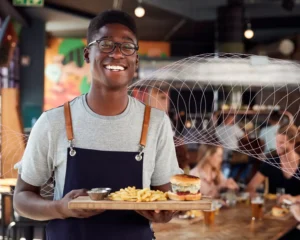 Male server smiling while holding tray of burger and fries