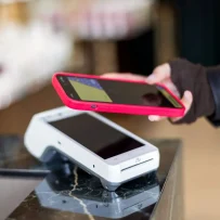 Customer using a smartphone to make a contactless payment on a restaurant POS terminal