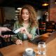 Customer making a contactless card payment at a restaurant table using a mobile payment device
