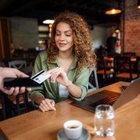 Customer making a contactless card payment at a restaurant table using a mobile payment device