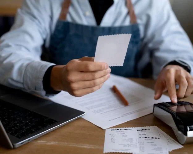 Restaurant Operator Reviewing Receipts and Financial Records at Desk