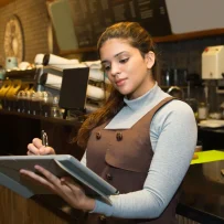 Restaurant employee reviewing financial reports at the counter of a multi-unit restaurant