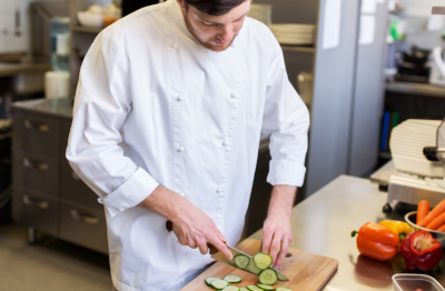 Cook cutting vegetables in restaurant kitchen