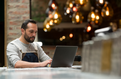 Man working in restaurant looking at laptop