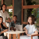 Restaurant Owners Smiling At Camera in Empty Restaurant with Laptop