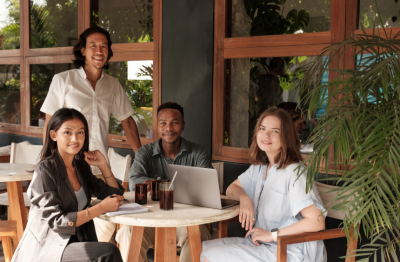 Restaurant Owners Smiling At Camera in Empty Restaurant with Laptop