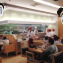 Close-up of security cameras monitoring a busy restaurant, highlighting loss prevention