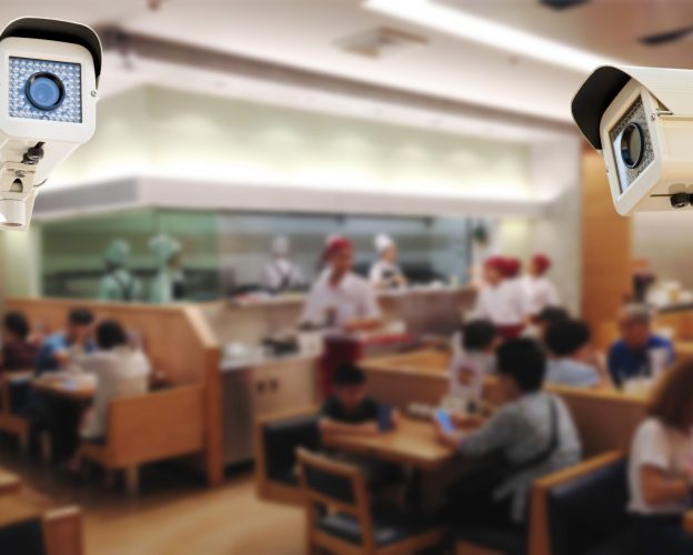 Close-up of security cameras monitoring a busy restaurant, highlighting loss prevention