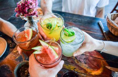 Friends toasting, saying cheers holding tropical blended fruit margaritas