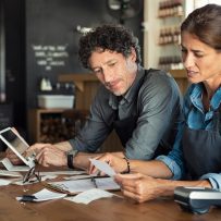 Man and woman sitting in cafeteria discussing finances for the month