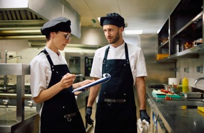 Two cooks review a checklist in the restaurant kitchen